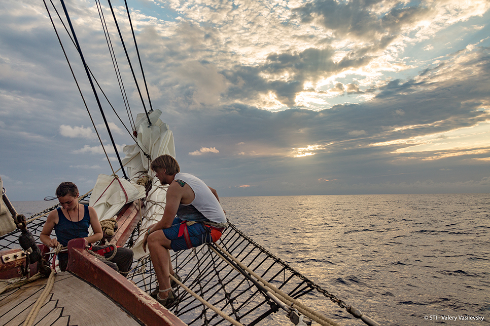 sailors sat on bowsprit of a tall ship